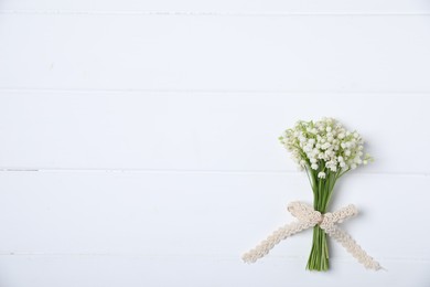 Photo of Bouquet of beautiful lily-of-the-valley flowers on white wooden background, top view. Space for text