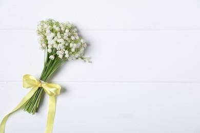 Photo of Bouquet of beautiful lily-of-the-valley flowers on white wooden background, top view. Space for text