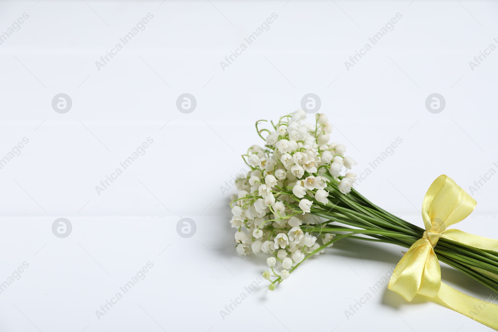 Bouquet of beautiful lily-of-the-valley flowers on white wooden background, closeup. Space for text Photo of Bouquet of beautiful lily-of-the-valley flowers on white wooden background, closeup. Space for text
