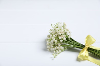 Photo of Bouquet of beautiful lily-of-the-valley flowers on white wooden background, closeup. Space for text