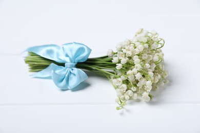 Photo of Bouquet of beautiful lily-of-the-valley flowers on white wooden background, closeup