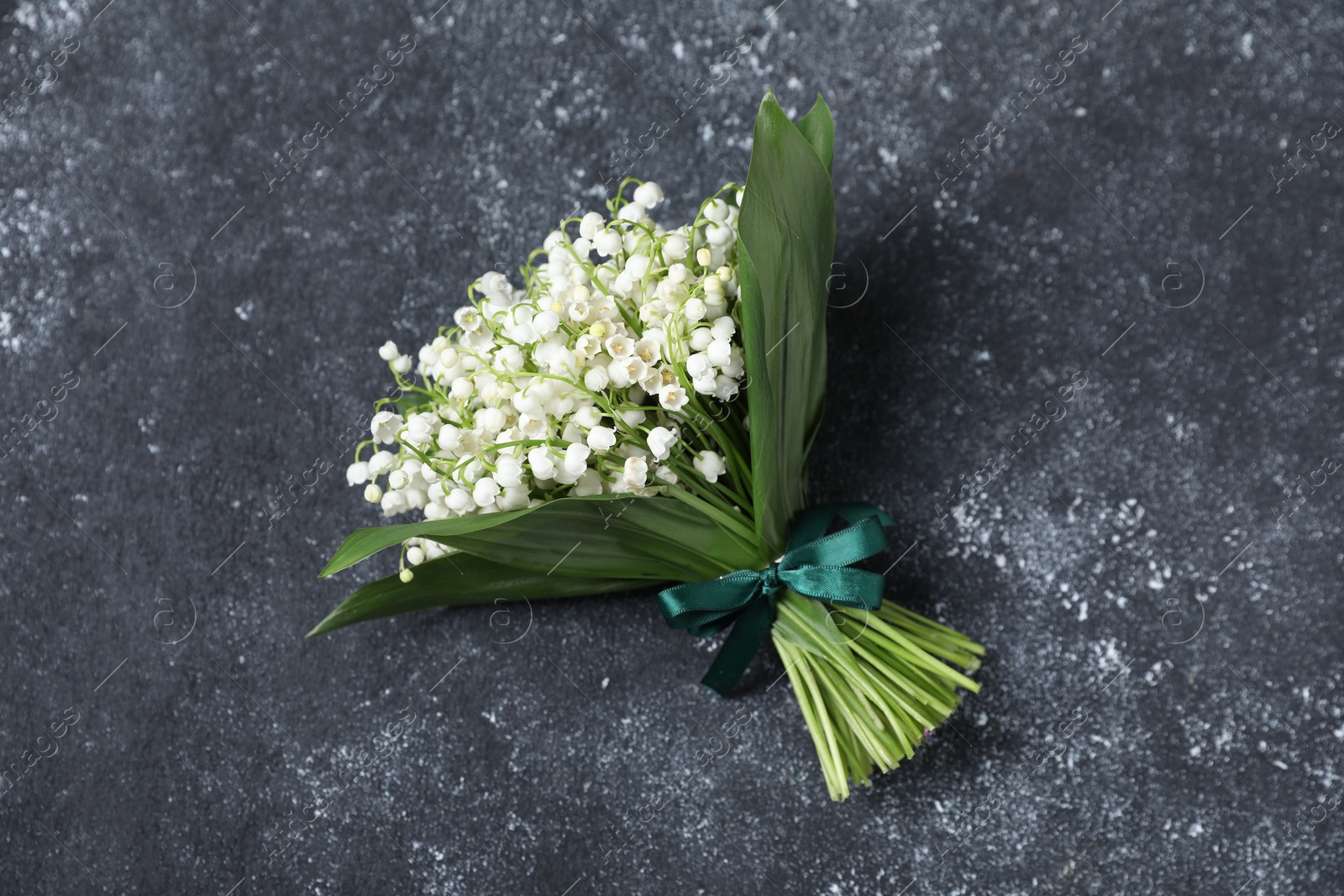 Bouquet of beautiful lily-of-the-valley flowers on black textured background, top view Photo of Bouquet of beautiful lily-of-the-valley flowers on black textured background, top view