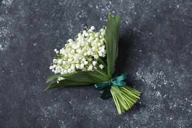 Photo of Bouquet of beautiful lily-of-the-valley flowers on black textured background, top view