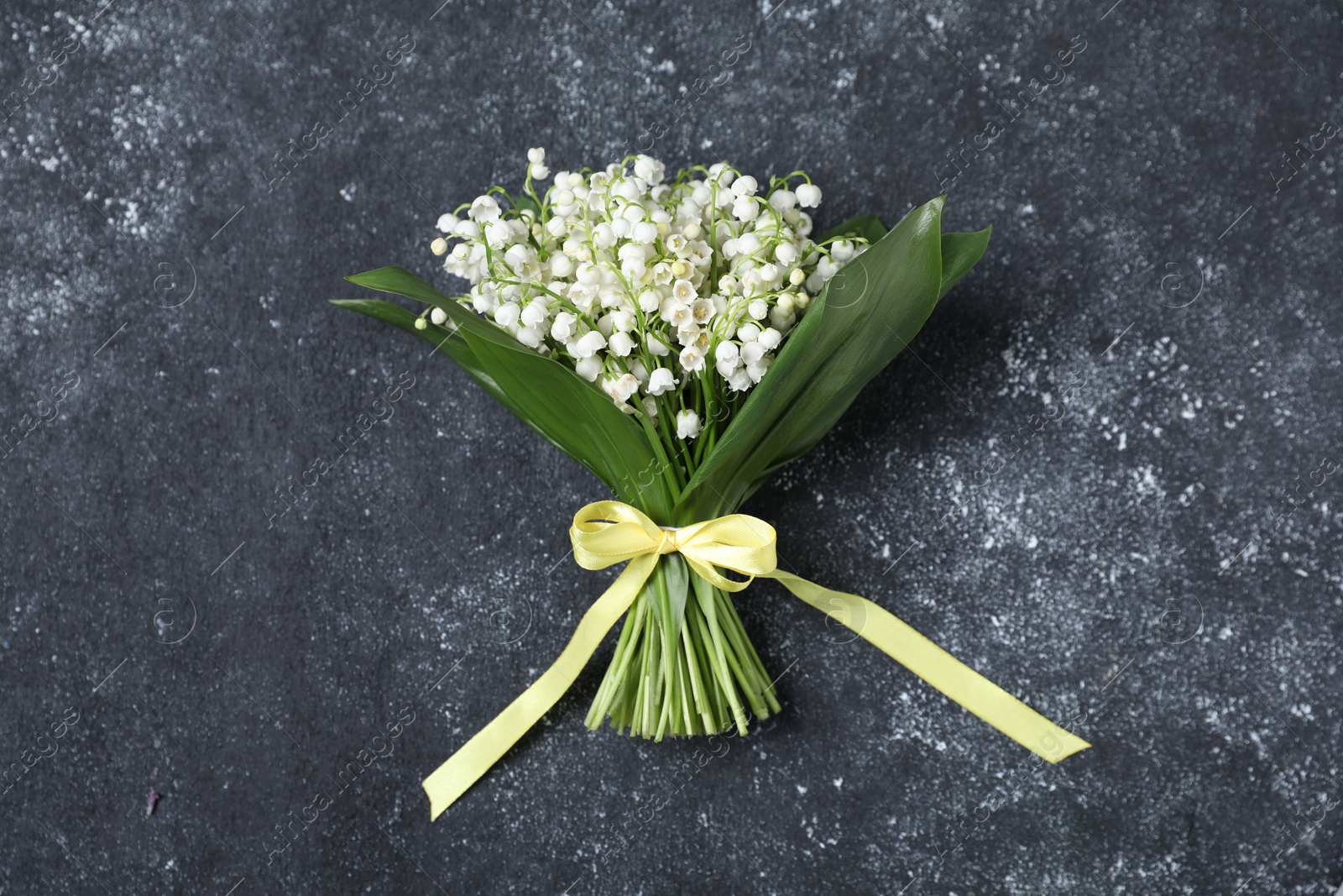 Bouquet of beautiful lily-of-the-valley flowers on black textured background, top view Photo of Bouquet of beautiful lily-of-the-valley flowers on black textured background, top view