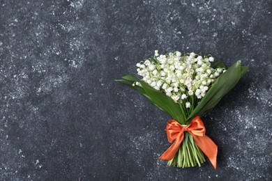 Photo of Bouquet of beautiful lily-of-the-valley flowers on black textured background, top view. Space for text