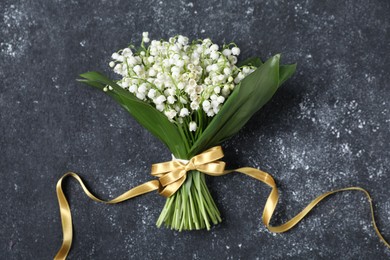 Photo of Bouquet of beautiful lily-of-the-valley flowers on black textured background, top view