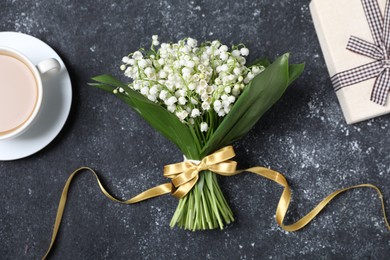 Photo of Bouquet of beautiful lily-of-the-valley flowers, gift and coffee on black textured background, flat lay
