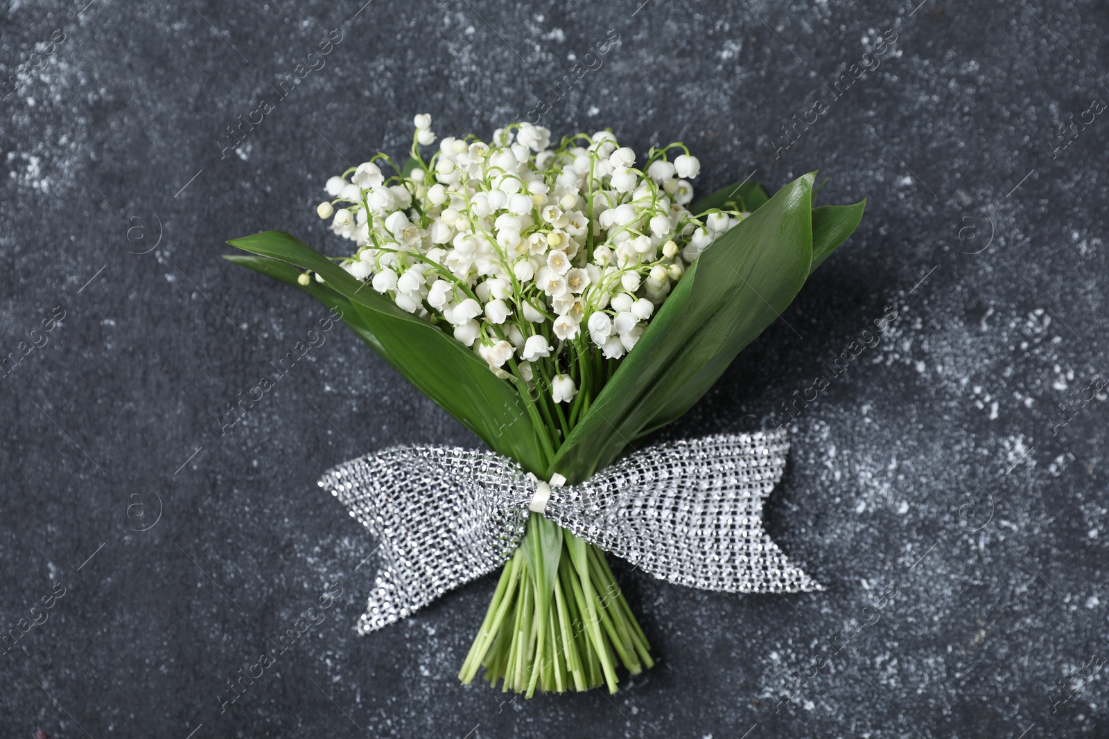 Bouquet of beautiful lily-of-the-valley flowers on black textured background, top view Photo of Bouquet of beautiful lily-of-the-valley flowers on black textured background, top view