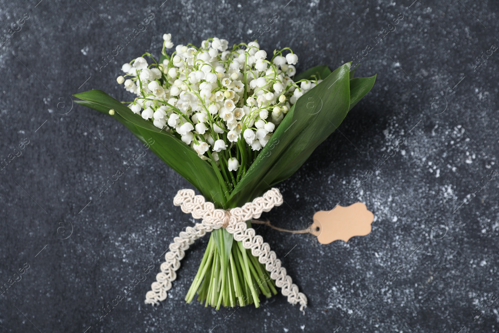 Bouquet of beautiful lily-of-the-valley flowers on black textured background, top view Photo of Bouquet of beautiful lily-of-the-valley flowers on black textured background, top view
