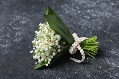 Photo of Bouquet of beautiful lily-of-the-valley flowers on black textured background, closeup