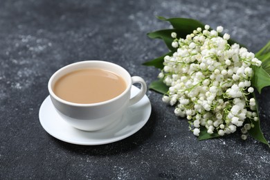 Photo of Bouquet of beautiful lily-of-the-valley flowers and coffee on black textured background, closeup
