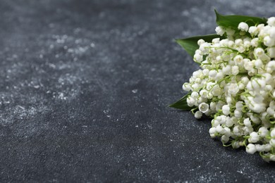 Photo of Bouquet of beautiful lily-of-the-valley flowers on black textured background, closeup. Space for text