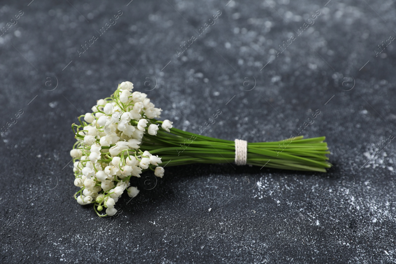 Bouquet of beautiful lily-of-the-valley flowers on black textured background, closeup Photo of Bouquet of beautiful lily-of-the-valley flowers on black textured background, closeup
