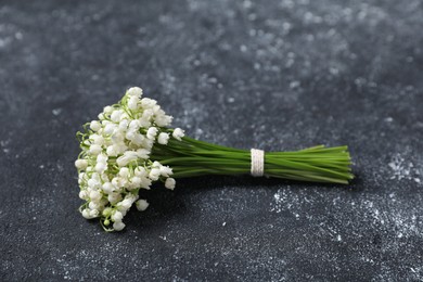 Photo of Bouquet of beautiful lily-of-the-valley flowers on black textured background, closeup