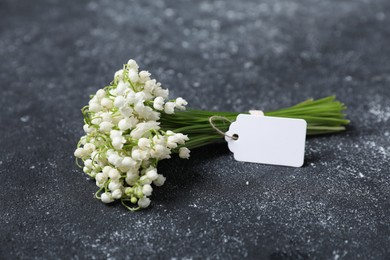 Photo of Bouquet of beautiful lily-of-the-valley flowers on black textured background, closeup