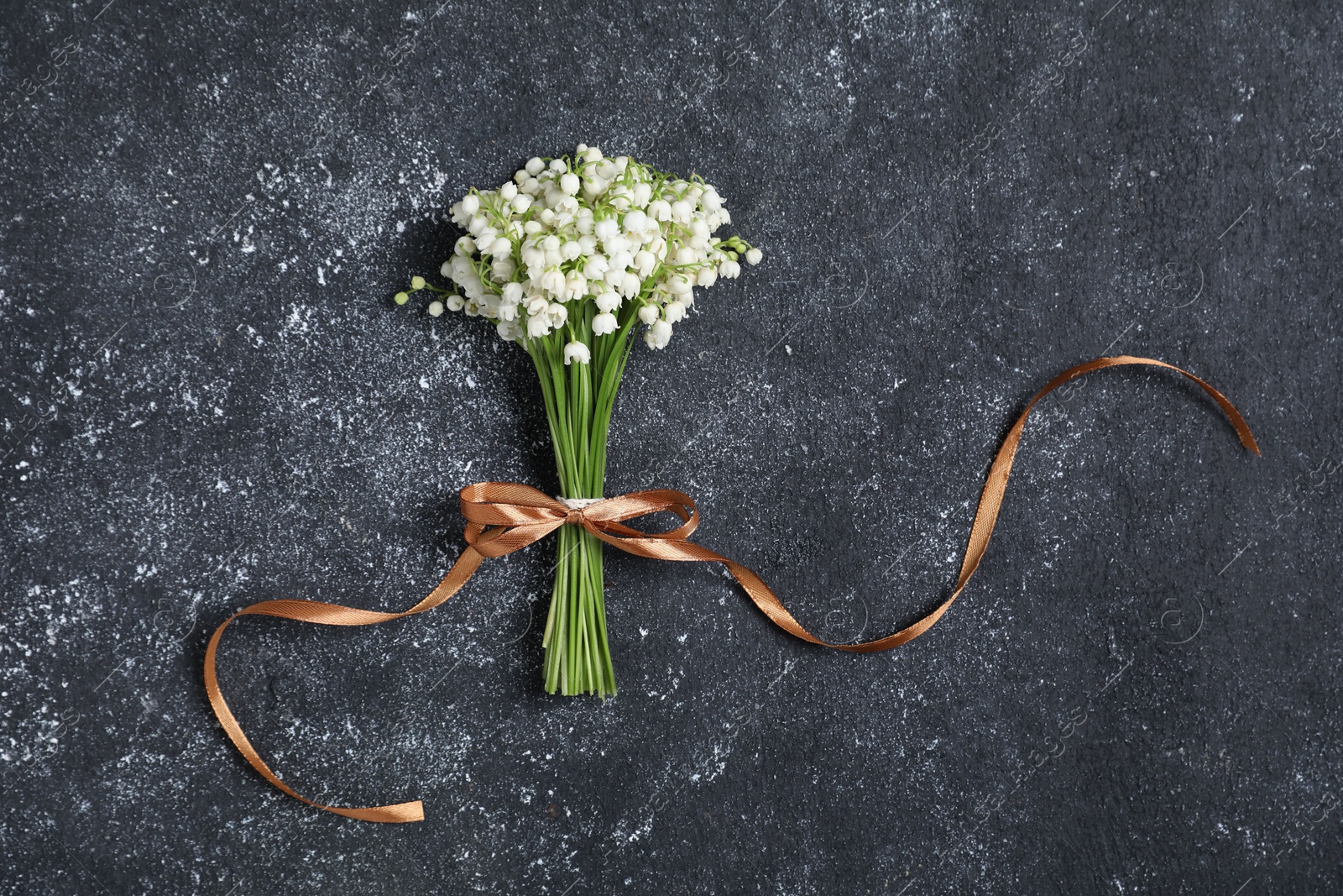 Bouquet of beautiful lily-of-the-valley flowers on black textured background, top view Photo of Bouquet of beautiful lily-of-the-valley flowers on black textured background, top view