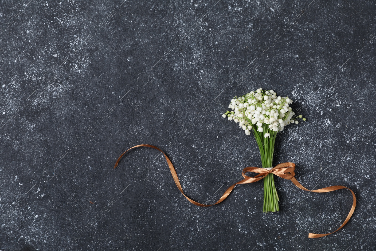 Bouquet of beautiful lily-of-the-valley flowers on black textured background, top view. Space for text Photo of Bouquet of beautiful lily-of-the-valley flowers on black textured background, top view. Space for text
