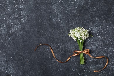 Photo of Bouquet of beautiful lily-of-the-valley flowers on black textured background, top view. Space for text