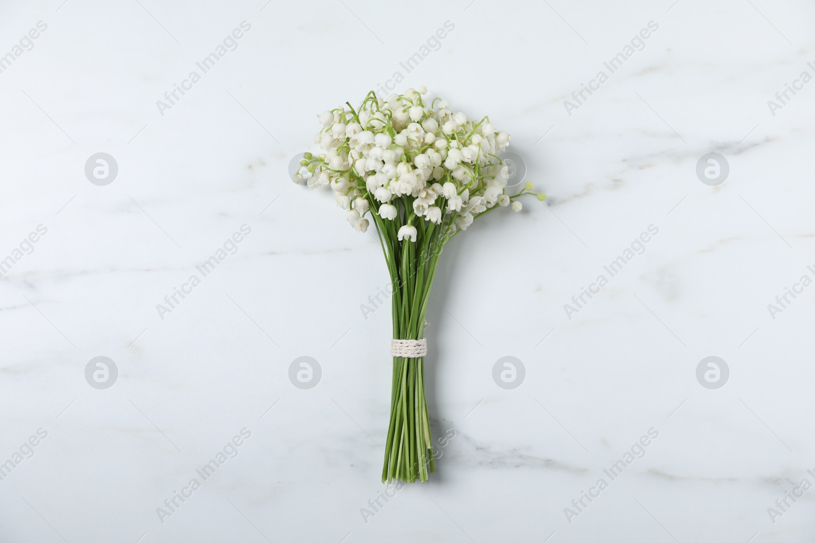 Bouquet of beautiful lily-of-the-valley flowers on white marble background, top view Photo of Bouquet of beautiful lily-of-the-valley flowers on white marble background, top view