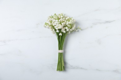 Photo of Bouquet of beautiful lily-of-the-valley flowers on white marble background, top view
