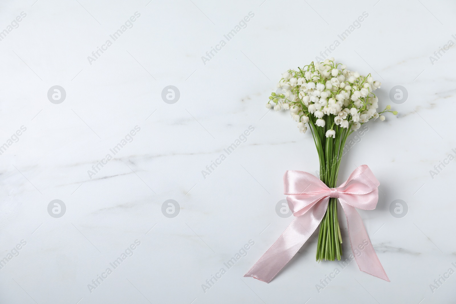 Bouquet of beautiful lily-of-the-valley flowers on white marble background, top view. Space for text Photo of Bouquet of beautiful lily-of-the-valley flowers on white marble background, top view. Space for text