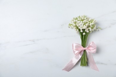 Photo of Bouquet of beautiful lily-of-the-valley flowers on white marble background, top view. Space for text