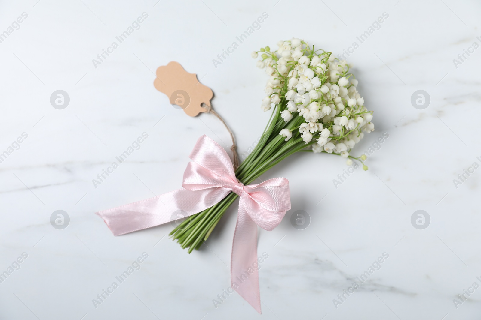 Bouquet of beautiful lily-of-the-valley flowers on white marble background, top view Photo of Bouquet of beautiful lily-of-the-valley flowers on white marble background, top view