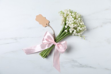 Photo of Bouquet of beautiful lily-of-the-valley flowers on white marble background, top view