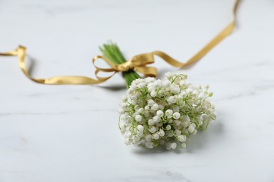 Photo of Bouquet of beautiful lily-of-the-valley flowers on white marble background, closeup