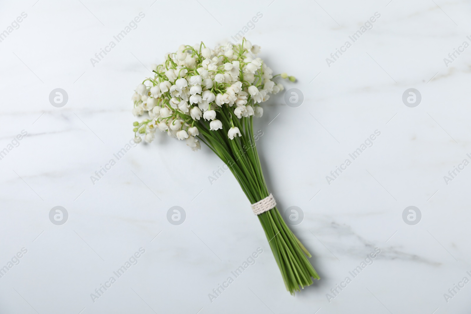 Bouquet of beautiful lily-of-the-valley flowers on white marble background, top view Photo of Bouquet of beautiful lily-of-the-valley flowers on white marble background, top view