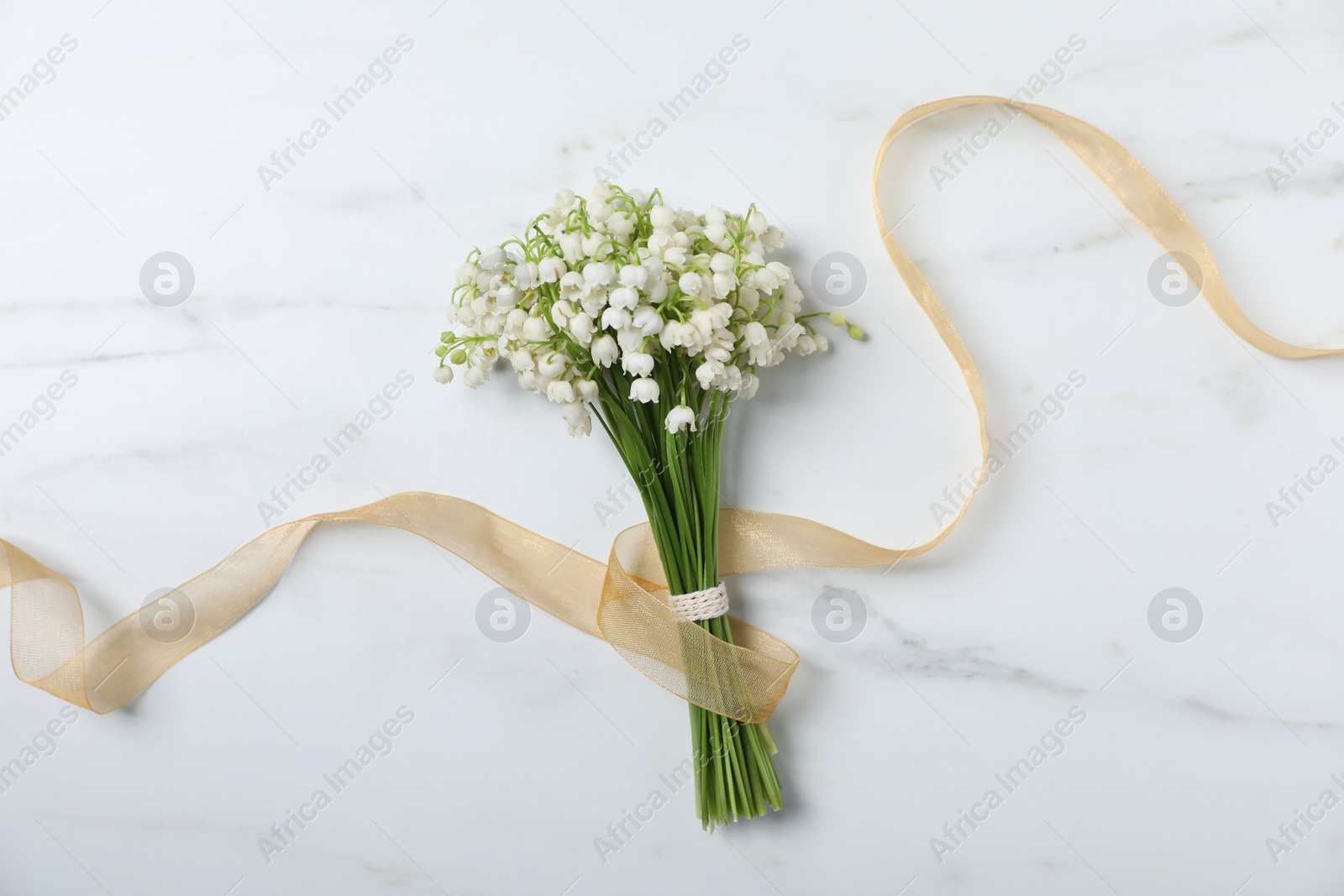 Bouquet of beautiful lily-of-the-valley flowers on white marble background, top view Photo of Bouquet of beautiful lily-of-the-valley flowers on white marble background, top view