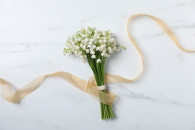 Photo of Bouquet of beautiful lily-of-the-valley flowers on white marble background, top view