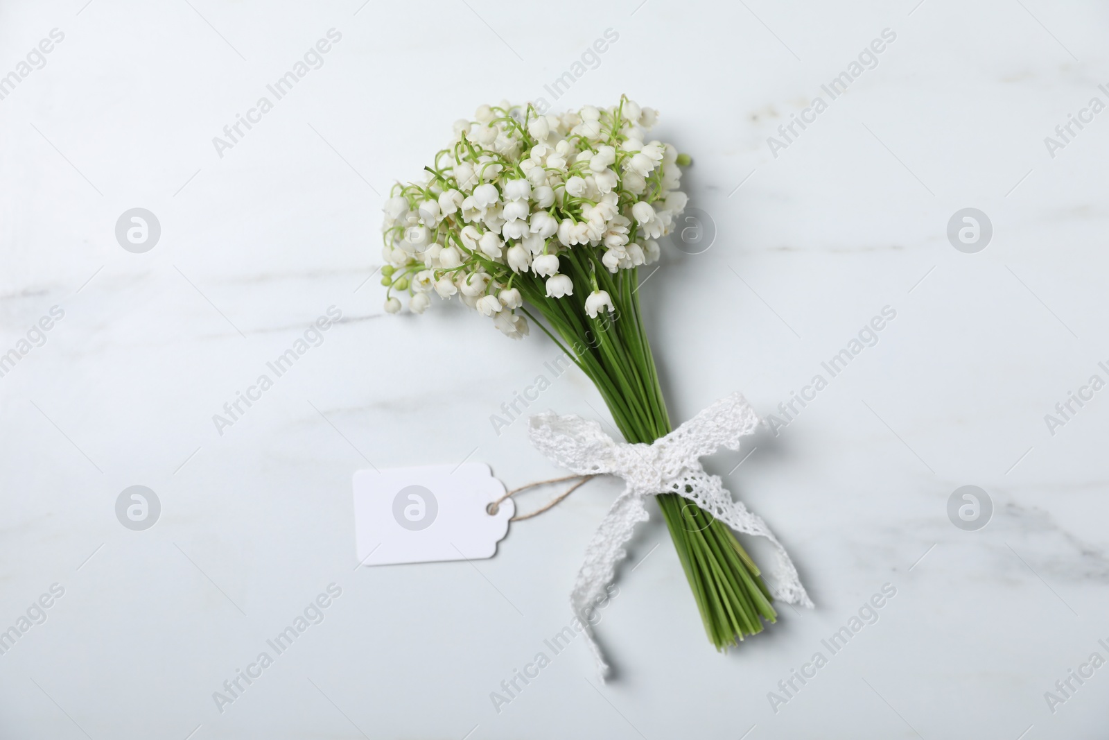 Bouquet of beautiful lily-of-the-valley flowers on white marble background, top view Photo of Bouquet of beautiful lily-of-the-valley flowers on white marble background, top view
