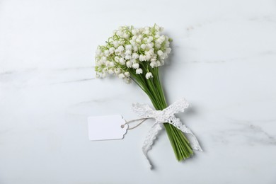 Photo of Bouquet of beautiful lily-of-the-valley flowers on white marble background, top view