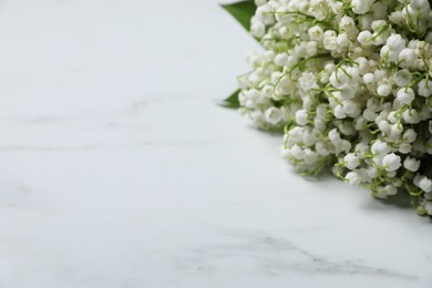 Photo of Bouquet of beautiful lily-of-the-valley flowers on white marble background, closeup. Space for text