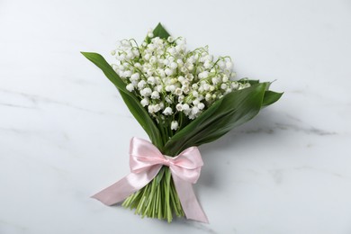 Photo of Bouquet of beautiful lily-of-the-valley flowers on white marble background, top view