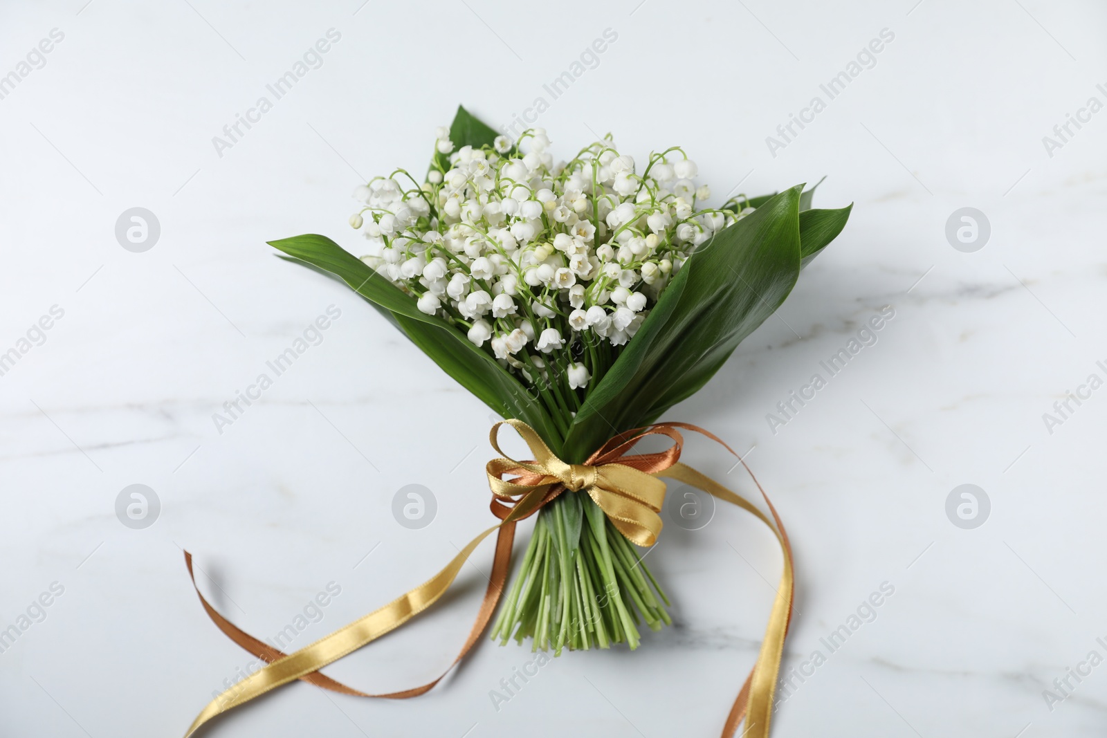 Bouquet of beautiful lily-of-the-valley flowers on white marble background, top view Photo of Bouquet of beautiful lily-of-the-valley flowers on white marble background, top view