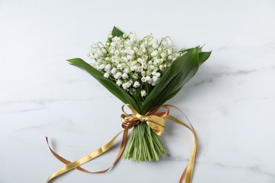 Photo of Bouquet of beautiful lily-of-the-valley flowers on white marble background, top view
