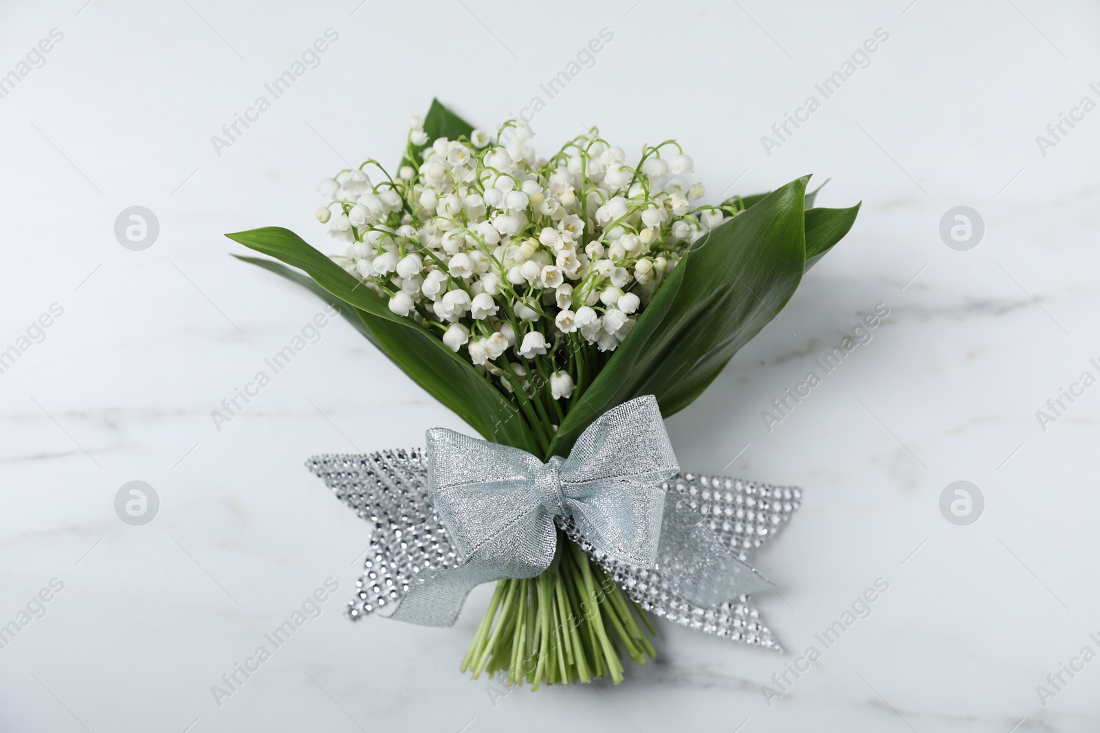 Bouquet of beautiful lily-of-the-valley flowers on white marble background, top view Photo of Bouquet of beautiful lily-of-the-valley flowers on white marble background, top view
