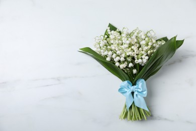 Photo of Bouquet of beautiful lily-of-the-valley flowers on white marble background, top view. Space for text