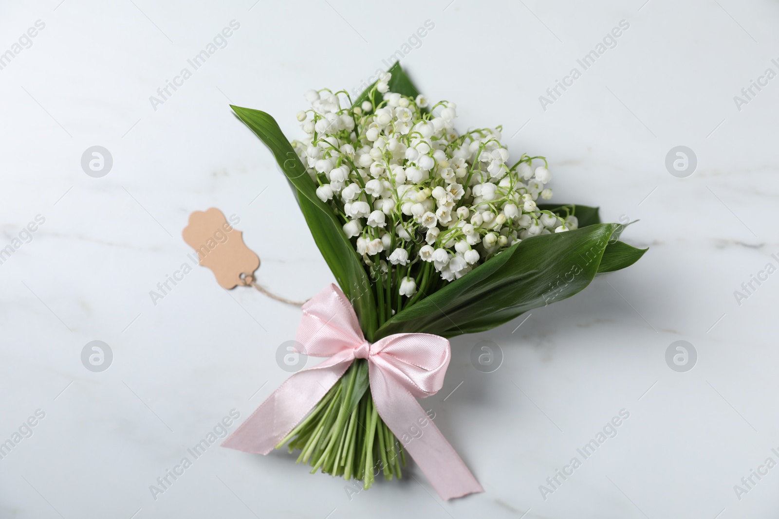 Bouquet of beautiful lily-of-the-valley flowers on white marble background, top view Photo of Bouquet of beautiful lily-of-the-valley flowers on white marble background, top view