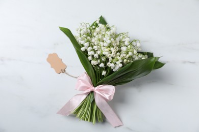 Photo of Bouquet of beautiful lily-of-the-valley flowers on white marble background, top view