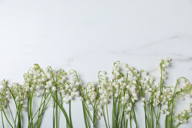Photo of Beautiful lily-of-the-valley flowers on white marble background, flat lay. Space for text