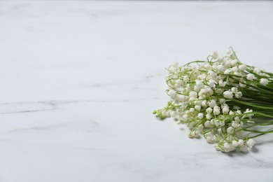 Photo of Beautiful lily-of-the-valley flowers on white marble background, closeup. Space for text