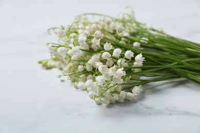 Photo of Beautiful lily-of-the-valley flowers on white marble background, closeup