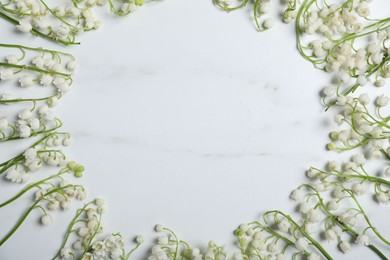Photo of Frame of beautiful lily-of-the-valley flowers on white marble background, flat lay. Space for text