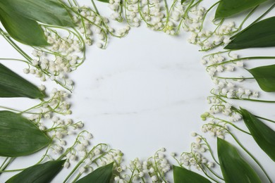 Photo of Frame of beautiful lily-of-the-valley flowers on white marble background, flat lay. Space for text