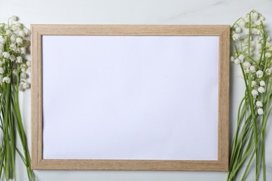 Photo of Beautiful lily-of-the-valley flowers and blank frame on white marble background, flat lay. Space for text