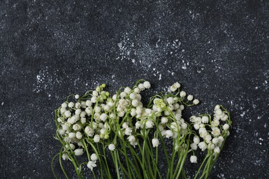 Photo of Beautiful lily-of-the-valley flowers on black textured background, flat lay. Space for text