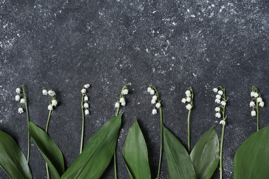 Photo of Beautiful lily-of-the-valley flowers on black textured background, flat lay. Space for text